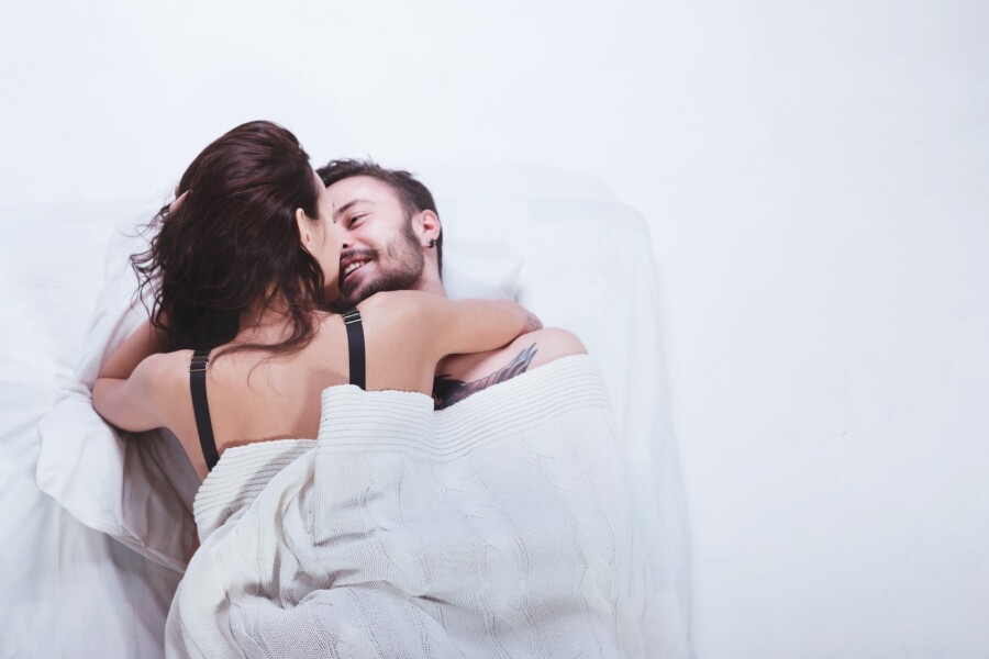 пара целуется под одеялом