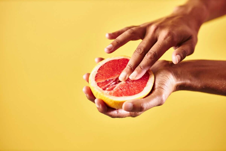 палец на половинке грейпфрута