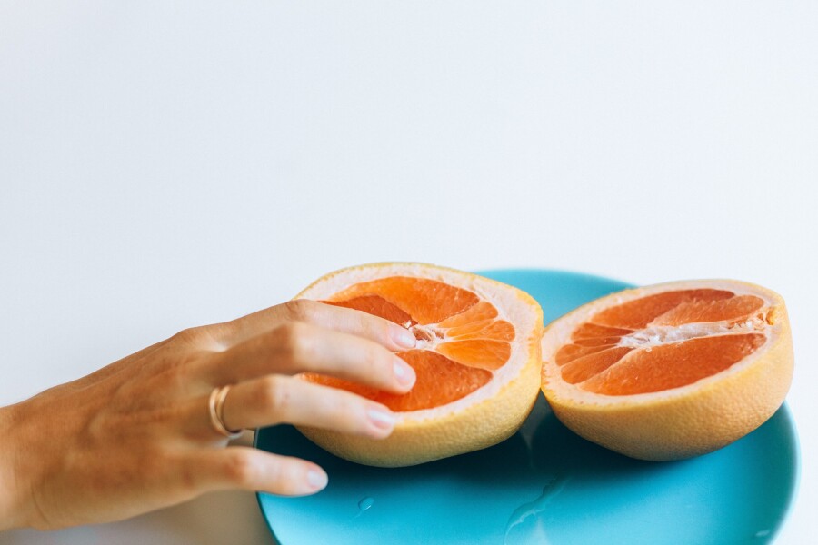 палец на половинке грейпфрута