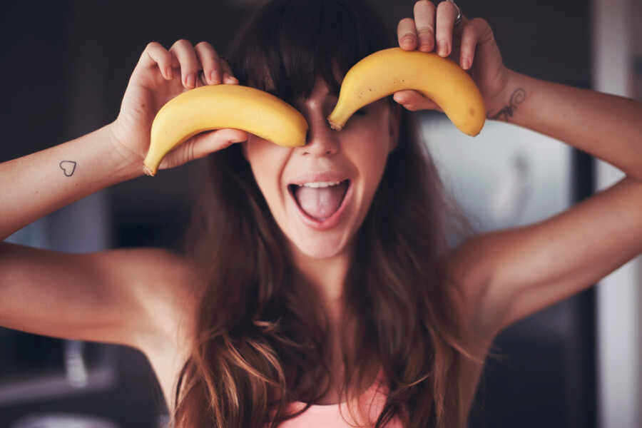 девушка держит бананы у глаз