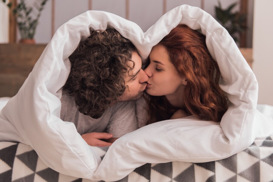 пара целуется под одеялом