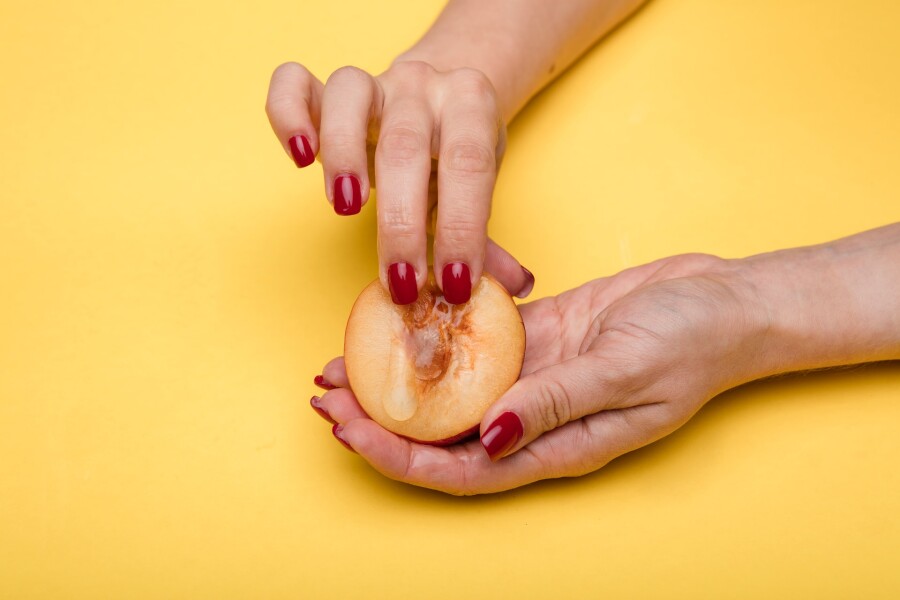пальцы на половинке персика