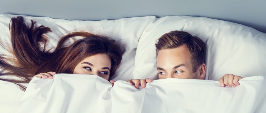 парень и девушка выглядывают из под одеяла