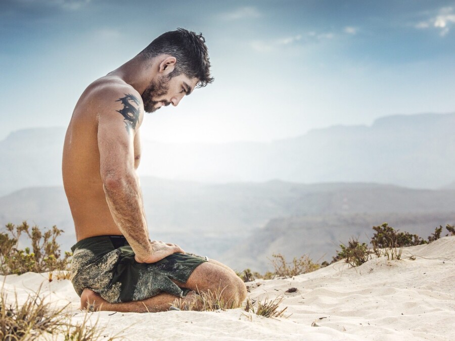 парень медитирует на песке
