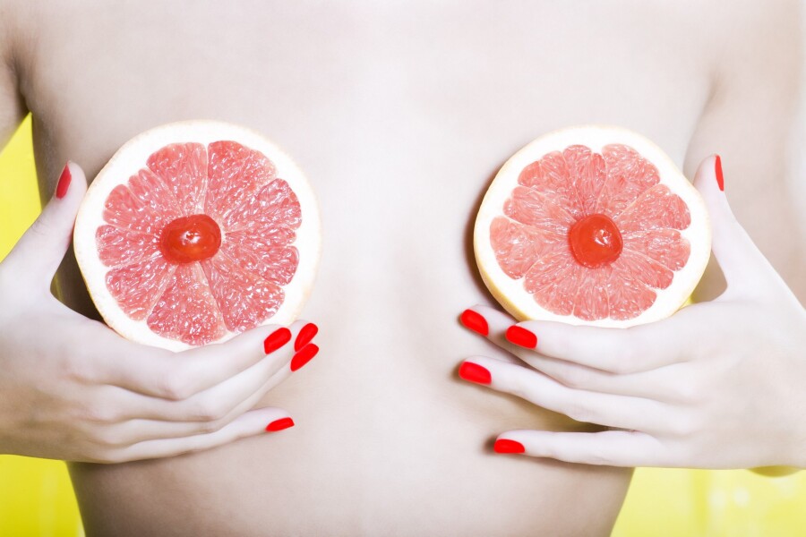 девушка держит грейпфрут у груди