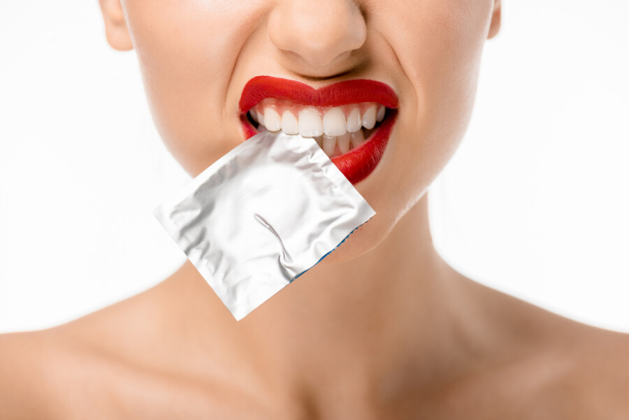 девушка держит презерватив в зубах