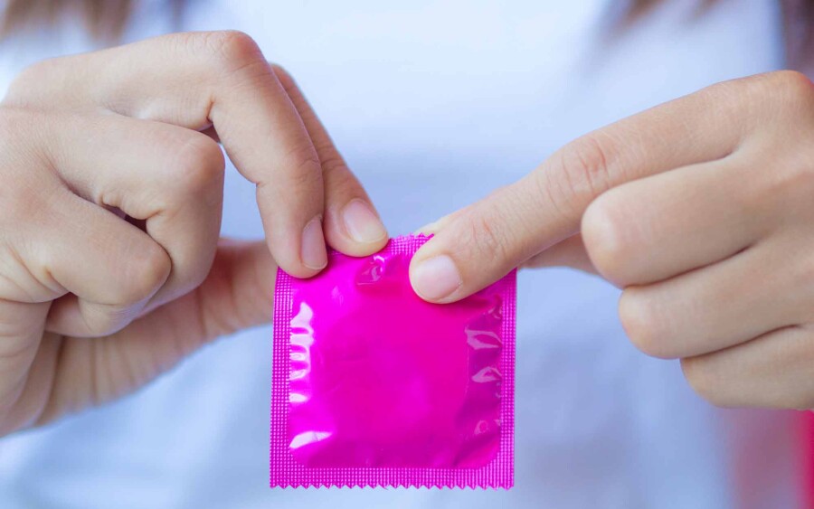 девушка открывает презерватив