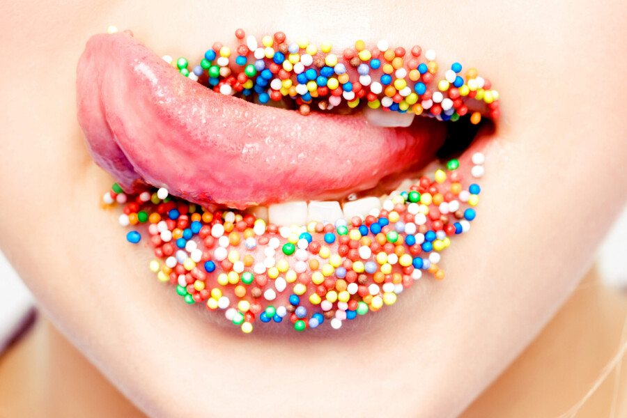 девушка облизывает губы в конфетах