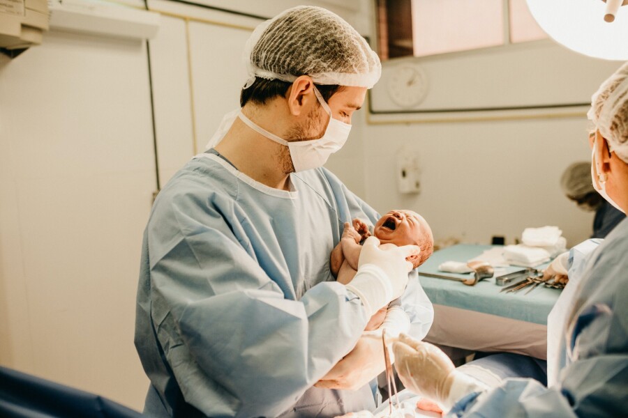 доктор с новорожденным ребенком
