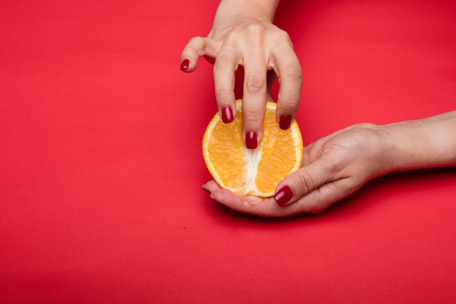 пальцы на половинке апельсина