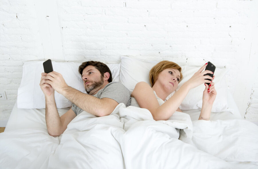 пара с телефонами в постели